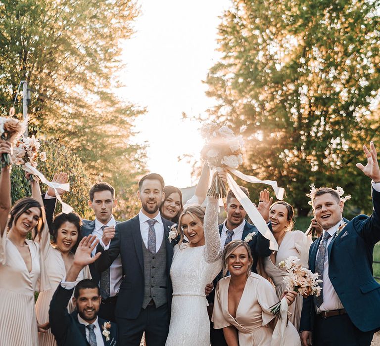 Wedding party with bride in beaded dress and groom in paisley tie and matching suits to groomsmen with bridesmaids in pale pink dresses