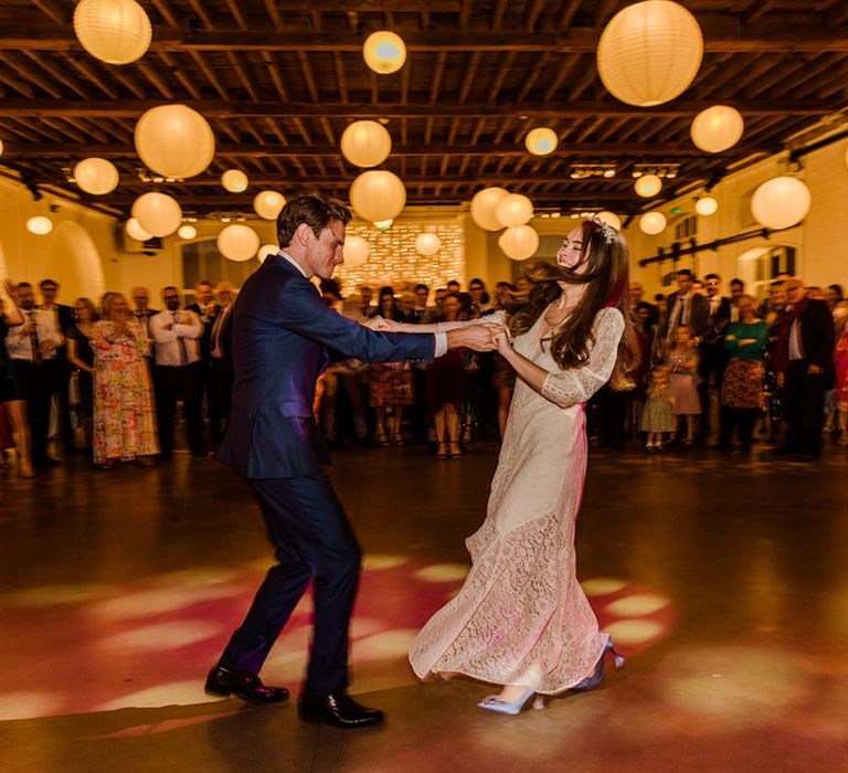 Bride and groom have their first dance together at city wedding in London with white hanging paper lanterns for decor 