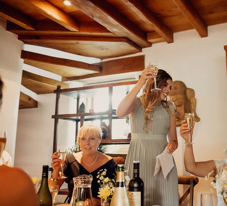 Bridesmaid in pleated green dress does a speech and holds a toast for the newlyweds 