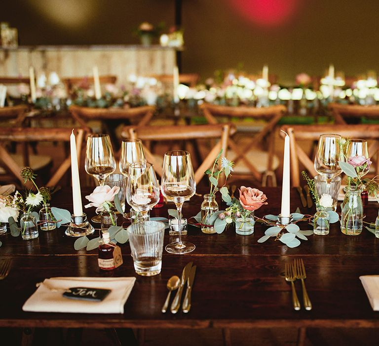 Roses and green foliage on banquet tables with gild cutlery and black name tags place cards