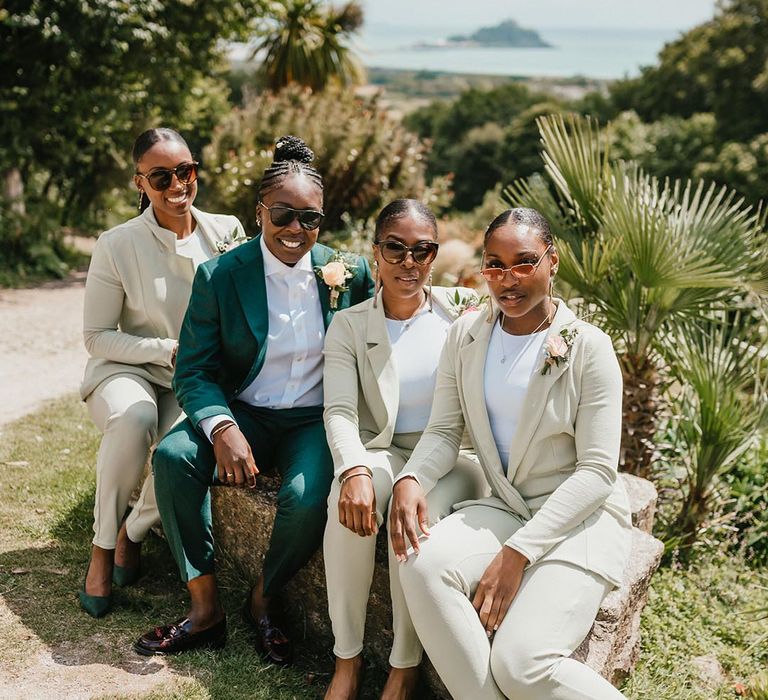 Bride at bridesmaids in green suits and sunglasses at outdoor Tremenheere Sculpture Gardens wedding 