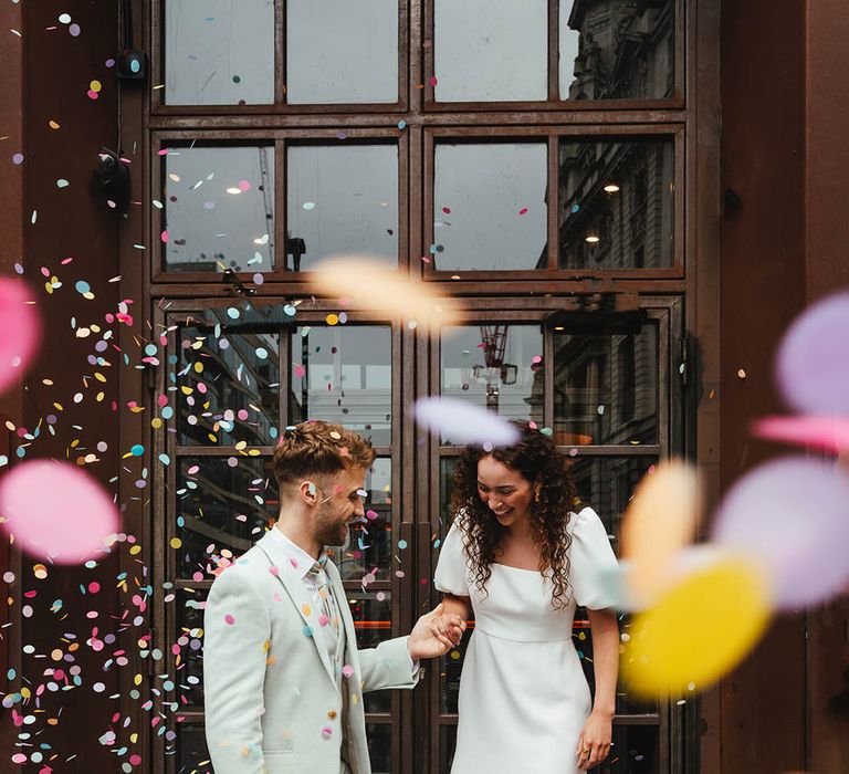 Confetti moment at Singer Tavern with bride in a Story Of My Dress short wedding dress and groom in a pale green suit and white trainers. 