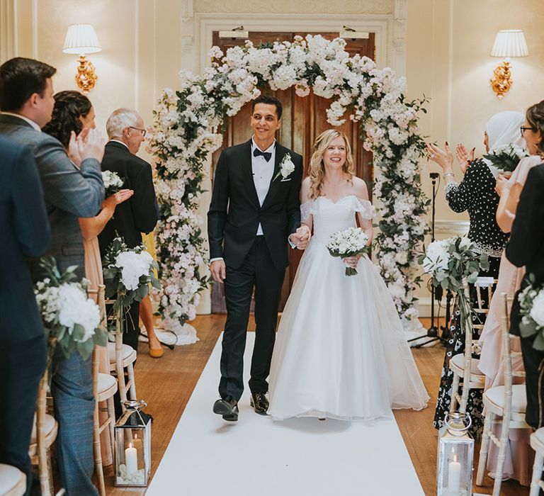 Bride and groom walk back down the aisle as a married couple for traditional style wedding 