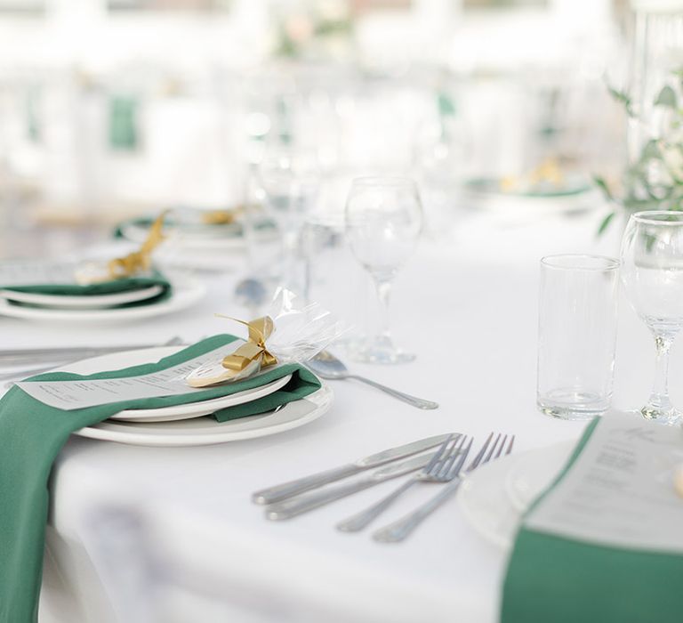 Green napkins placed on white plates complete with gold ribbon for reception at the Isla Gladstone Conservatory