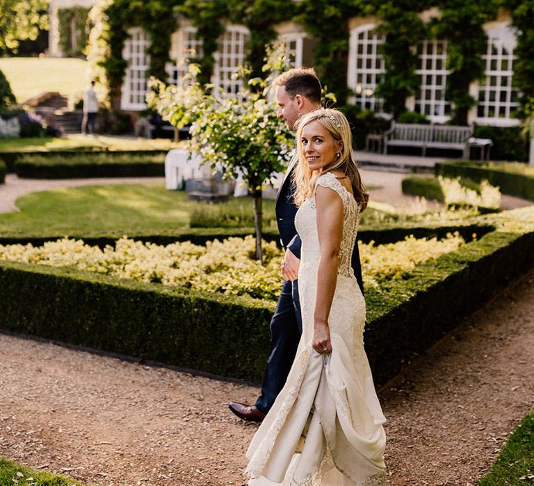 Bride in lace wedding dress looks at the camera as she walks around the gardens of Goldney Hall 