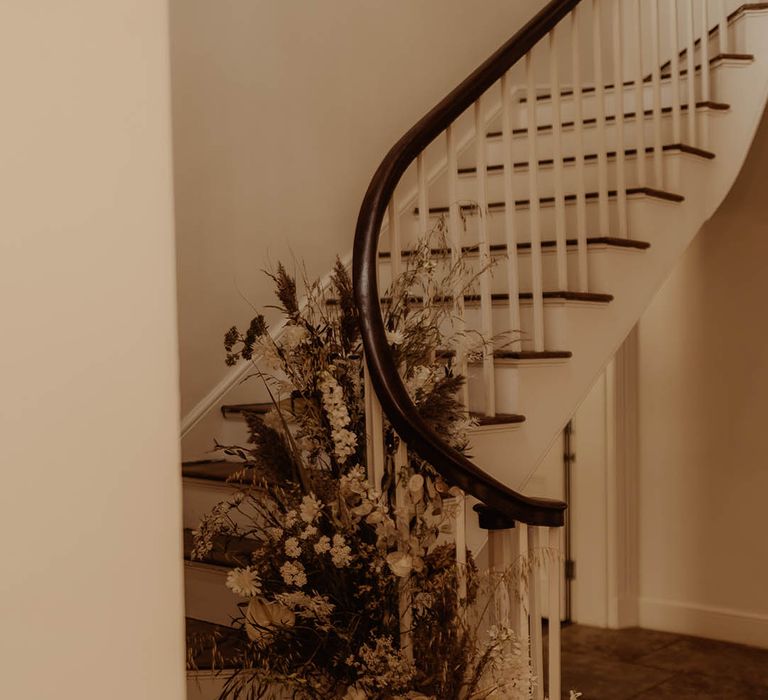 White and neutral fresh and dried flowers on a staircase for boho luxe wedding 