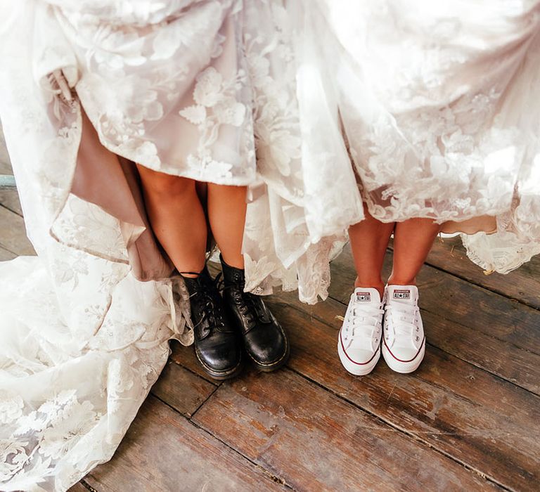 Brides in lace wedding dresses with both brides wearing flat shoes including Doc Martens and Converse