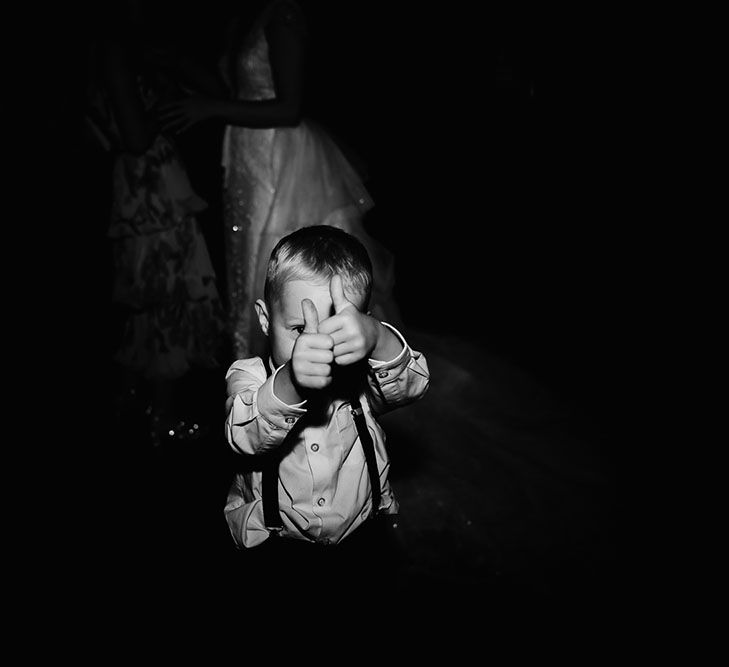 Little boy gives thumbs up during wedding reception in black and white image