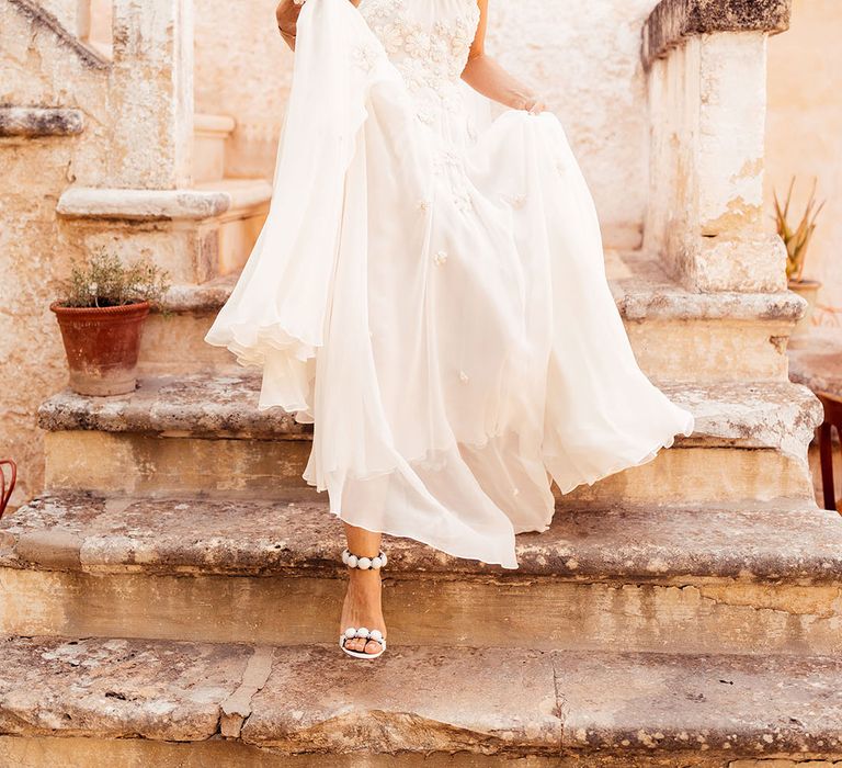 Bride with her blonde hair in a half up half down style in a flower halter neck wedding dress for a destination wedding 