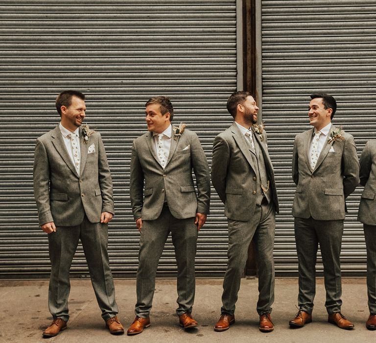 Groom and groomsmen wear grey suits complete with dried buttonholes and white pocket squares 