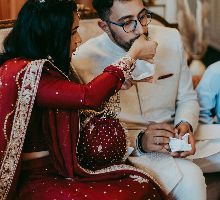 Bride feeds her groom during Nikkah Ceremony at Pakistani wedding with boho and Autumnal styled decor