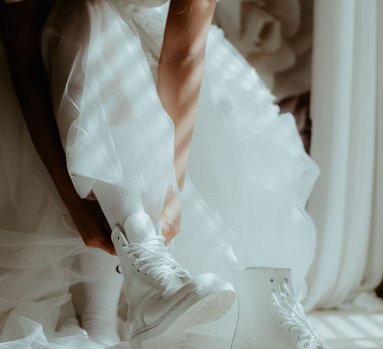 Bride in a tulle wedding dress wearing a white pair of Doc Martens 