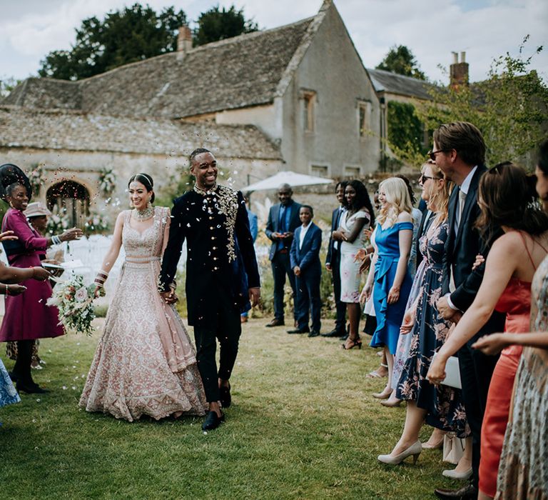 Bride and Groom walk through confetti throw at Cotswolds wedding venue, Caswell House