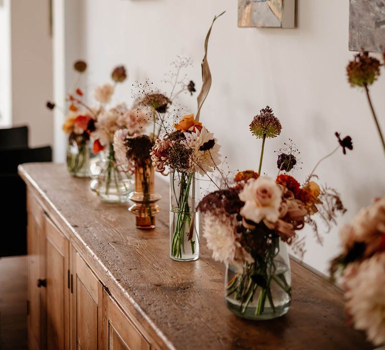 Small arrangements of wedding flowers in bud vases with a neutral autumnal wedding colour palette 