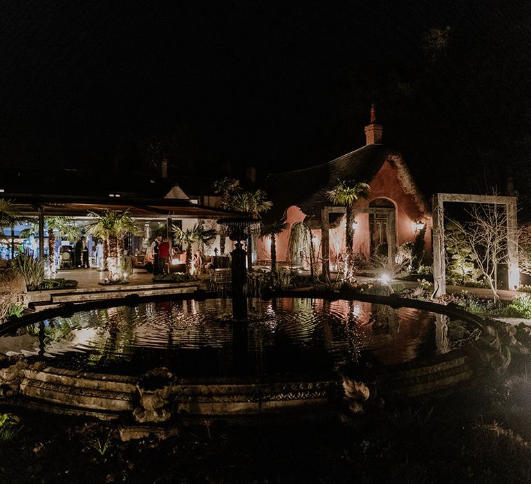 Le Petit Chateau at night surrounded by lights and water 