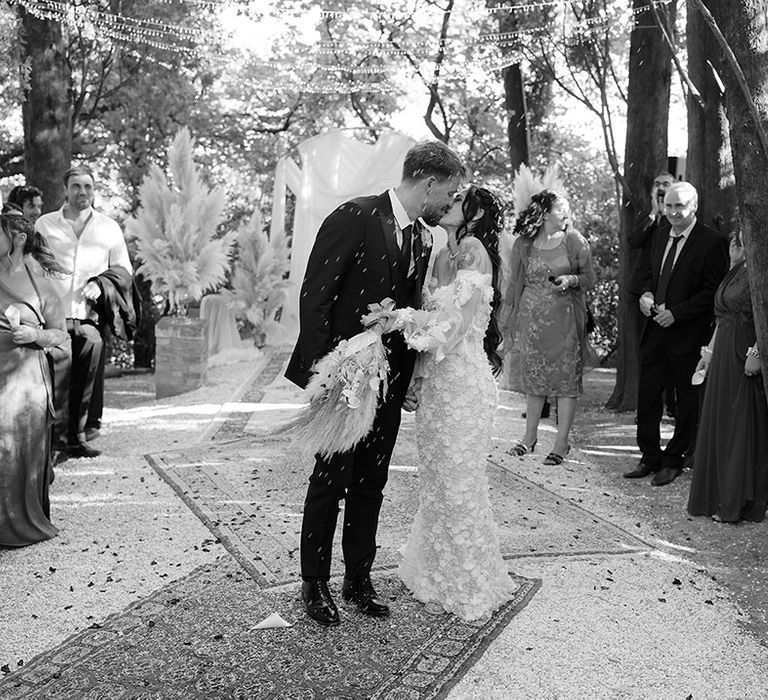 Bride & groom kiss during confetti exit during boho destination wedding 