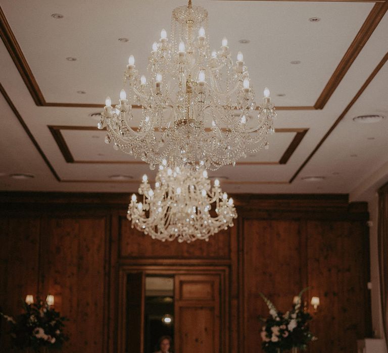 Chandelier hangs above round tables with white tablecloths and classic styling at Hedsor House