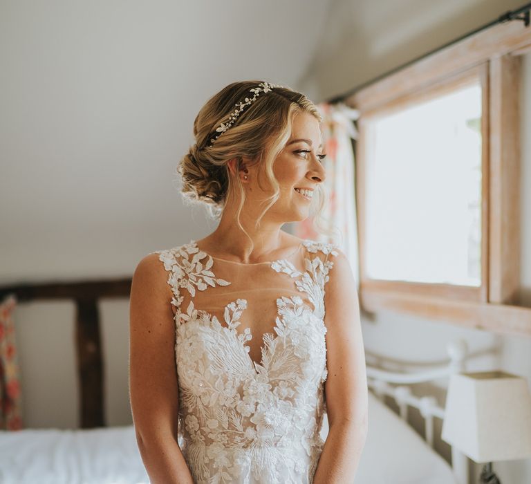 Bride in an illusion lace Dandon London wedding dress with her hair in a braided blonde updo with sparkly headpiece 