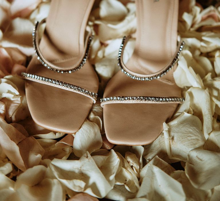 Sparkly nude bridal shoes surrounded by pastel petals