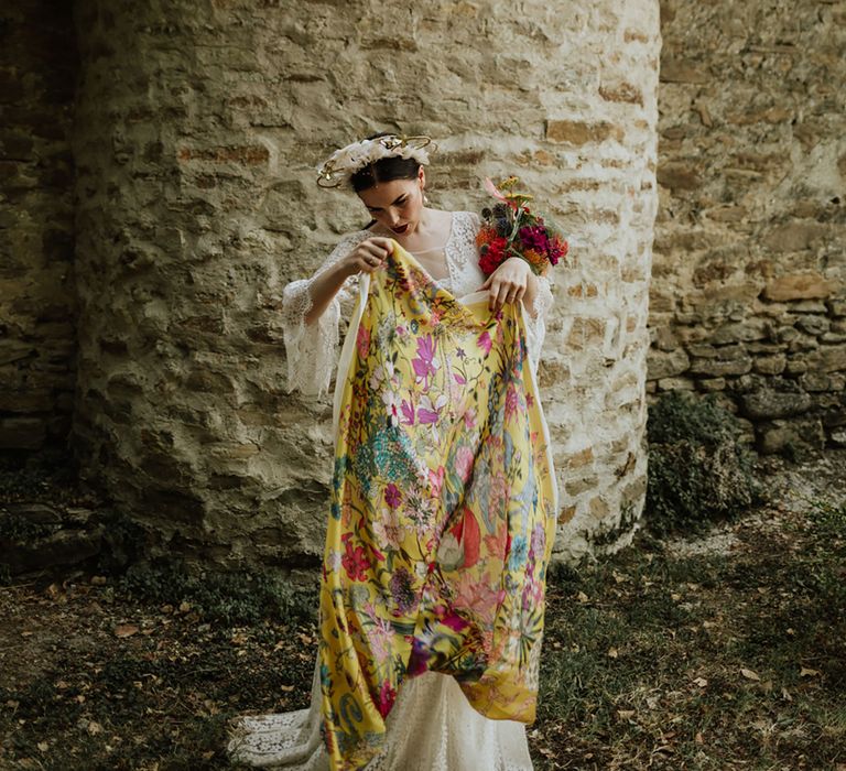 Bride in lace wedding dress and bridal crown carrying bright pink bridal bouquet and floral yellow pashmina