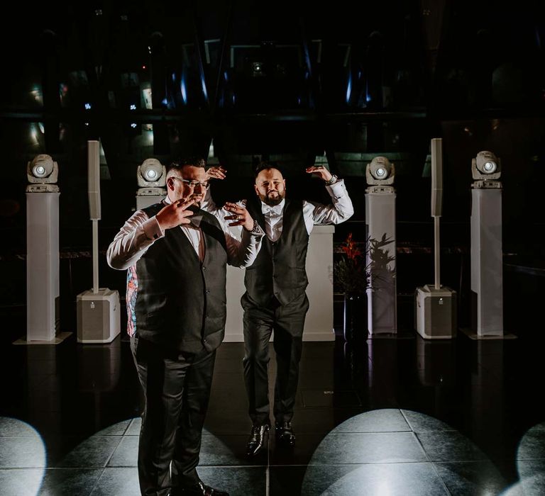 Grooms in matching black waistcoats, white shirts and black suit trousers dancing at wedding party at The Gherkin 