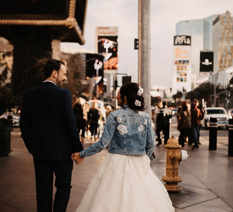 Bride wearing light blue denim jacket with pearls, white flowers and letters spelling out 'WIFEY' for Las Vegas wedding 