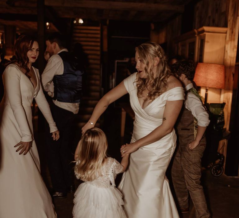 Bride in satin short sleeve deep v wedding dress and church length veil dancing with flower girl in short sleeve tulle layered flower girl dress at Hidden River Cabins 