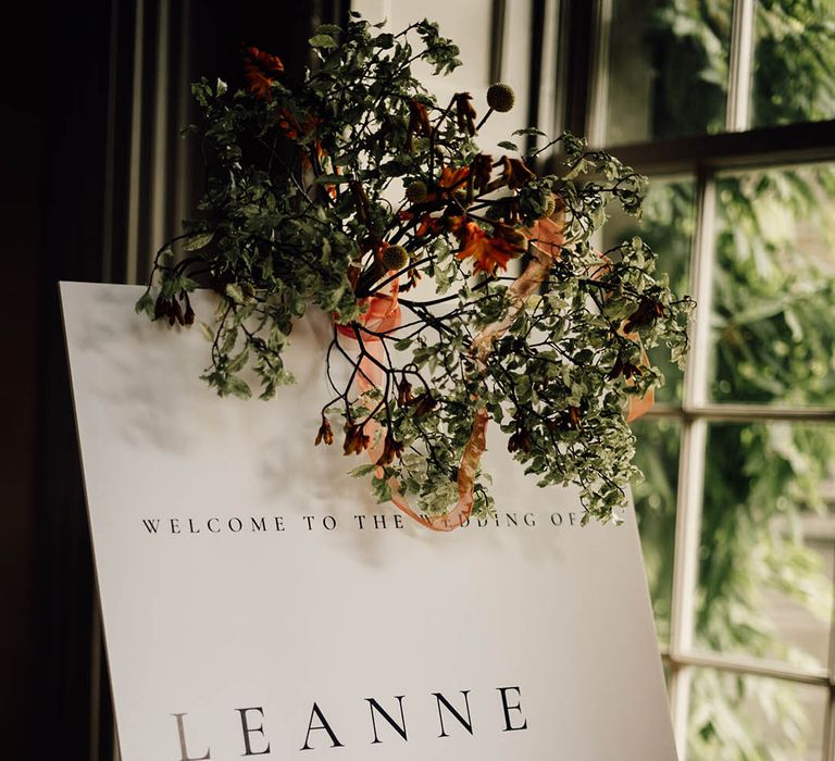 Black and white minimal wedding welcome sign decorated with foliage for classic wedding  