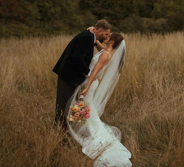 The bride and groom share a kiss in the field at The Pear Tree Purton 