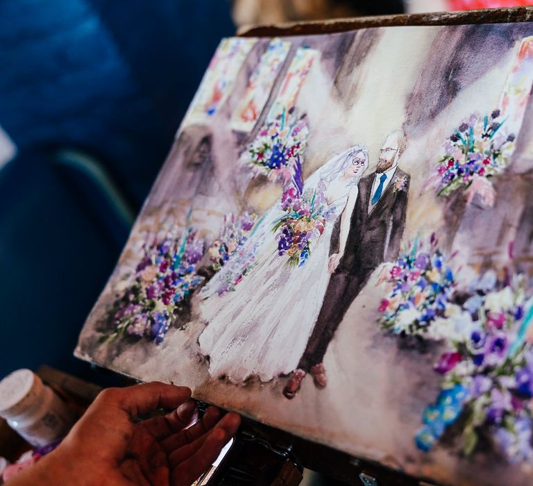 Stunning live wedding painting of the bride and groom surrounded by blue and purple wedding flower arrangements 