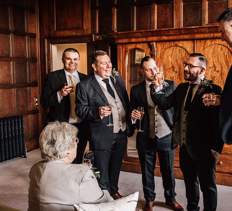 Groom stands around with the groomsmen drinking champagne on the morning of the wedding 