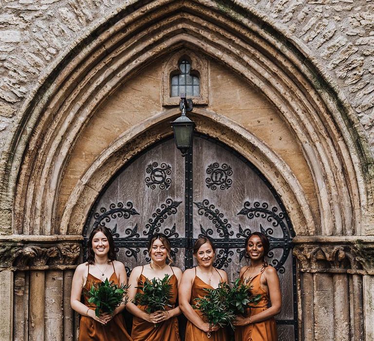 Bridal party in orange wrap bridesmaid dresses holding green bouquet 