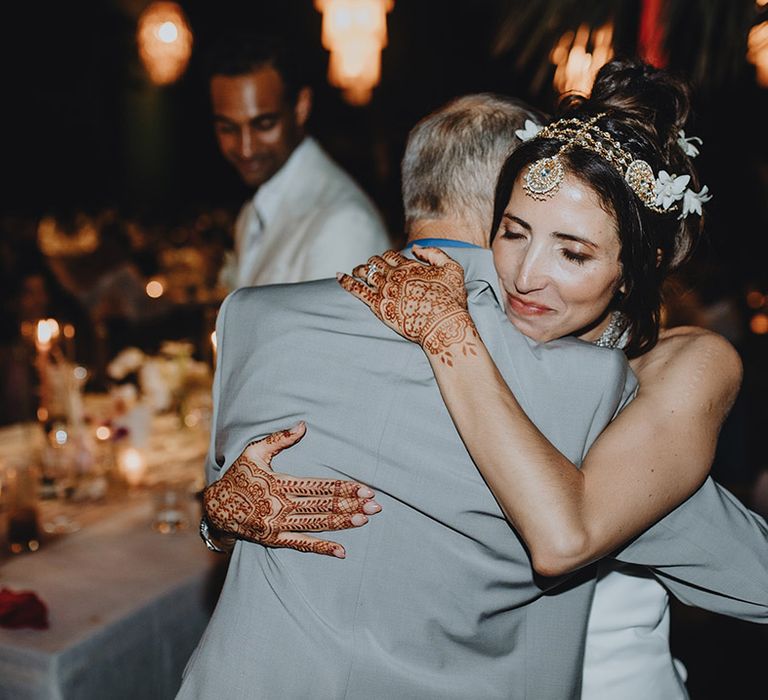 Bride embraces father of the bride with traditional henna tattoo on her hands