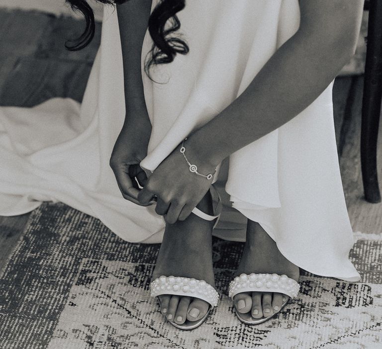 Bride puts on pearl wedding shoes 