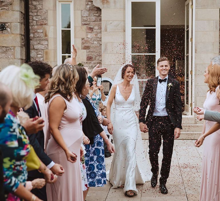 Confetti exit moment for the bride and groom at their traditional church ceremony 