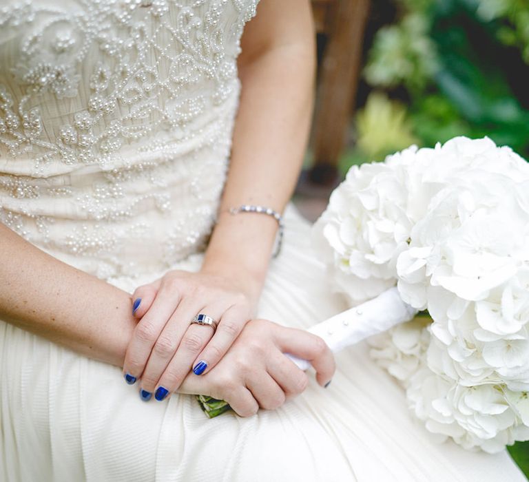 Bride wearing beaded wedding dress with bright purple colourful wedding nails