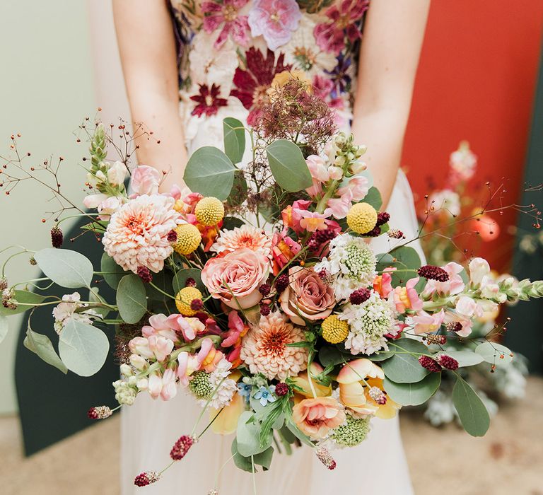 Bride in floral bodice wedding dress holding wildflower colourful wedding bouquet 