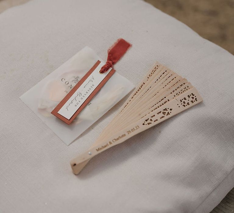 Wooden fan with pouches of confetti for wedding guests on their chairs 