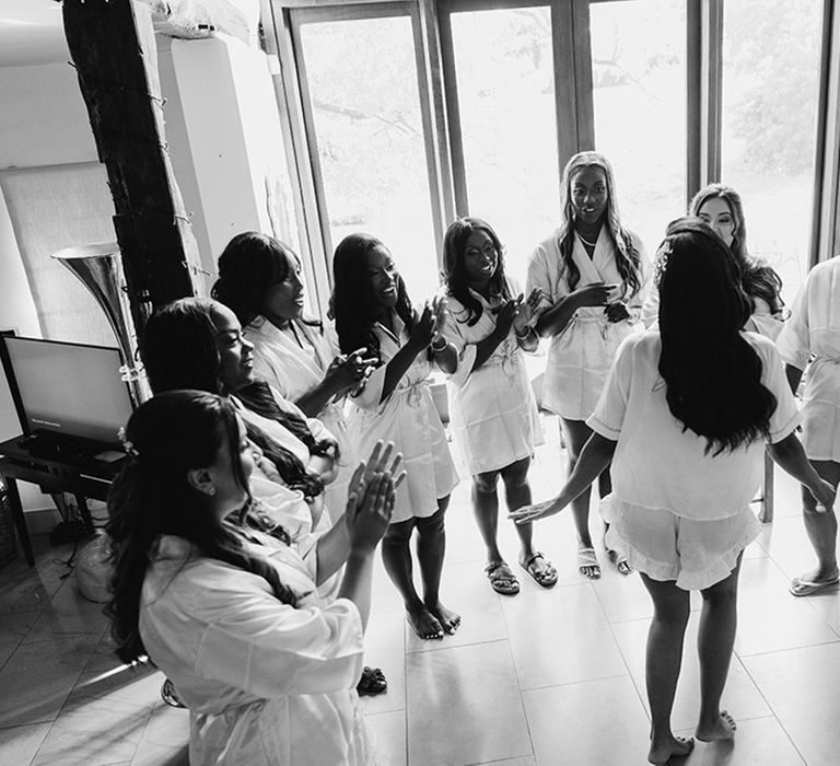 Bride and bridesmaids in white satin robes getting ready together 