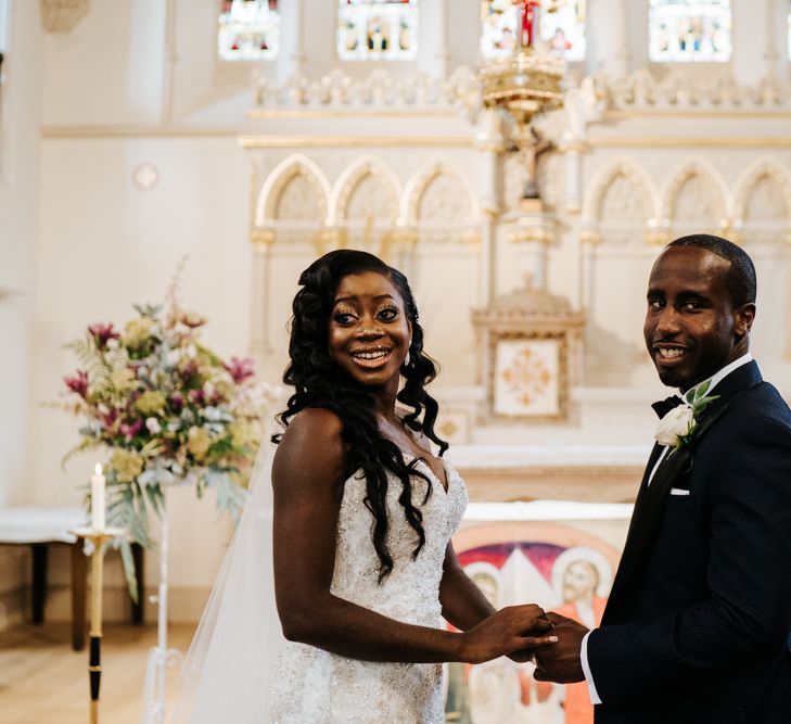 Bride and groom holding hands at their catholic wedding ceremony 