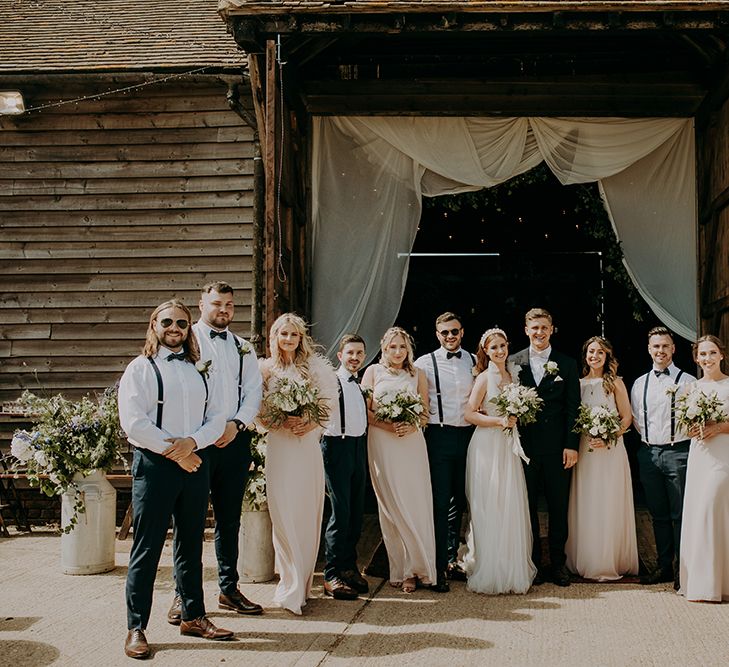 Wedding party portrait with bridesmaids in pink dresses and groomsmen in braces