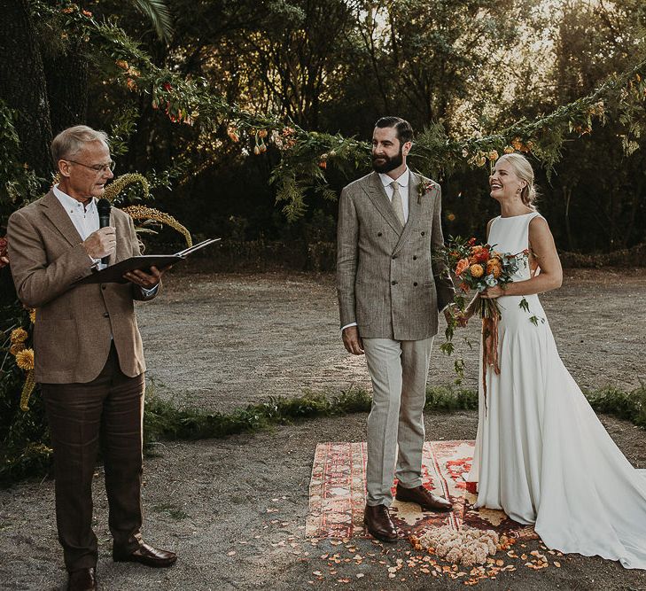 Bride and groom standing on a moroccan rug during woodland wedding ceremony 