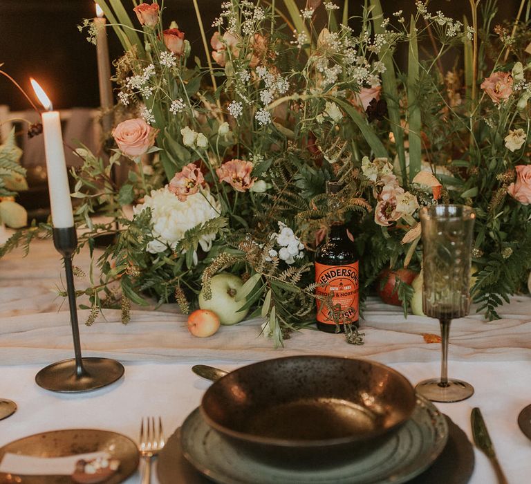 Place setting with coloured tableware, floral centrepiece and candles 