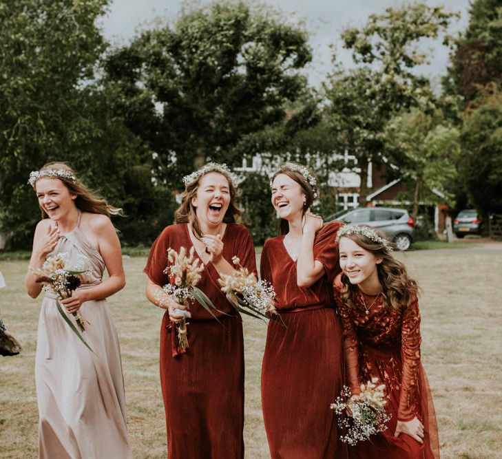 Bridesmaids laughing in rust coloured dresses 