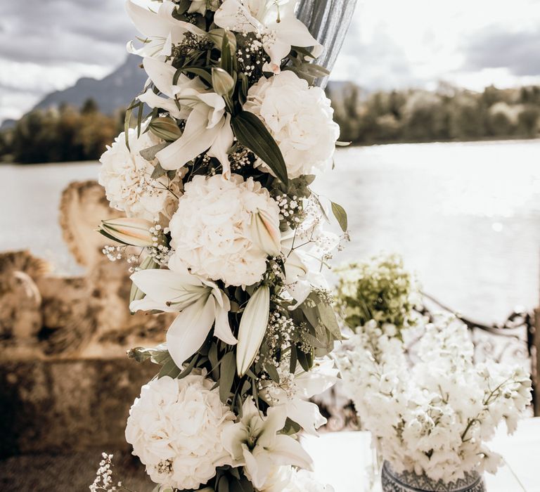 White lilies and hydrangea wedding flowers decorating the wooden framed altar 