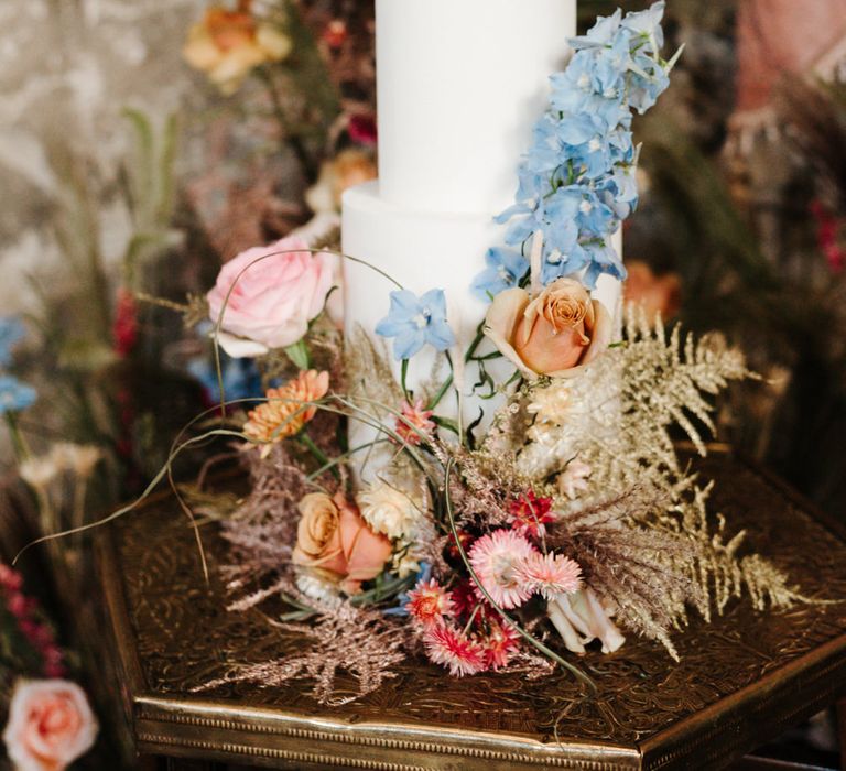 all white wedding cake decorated with colourful wedding flowers 