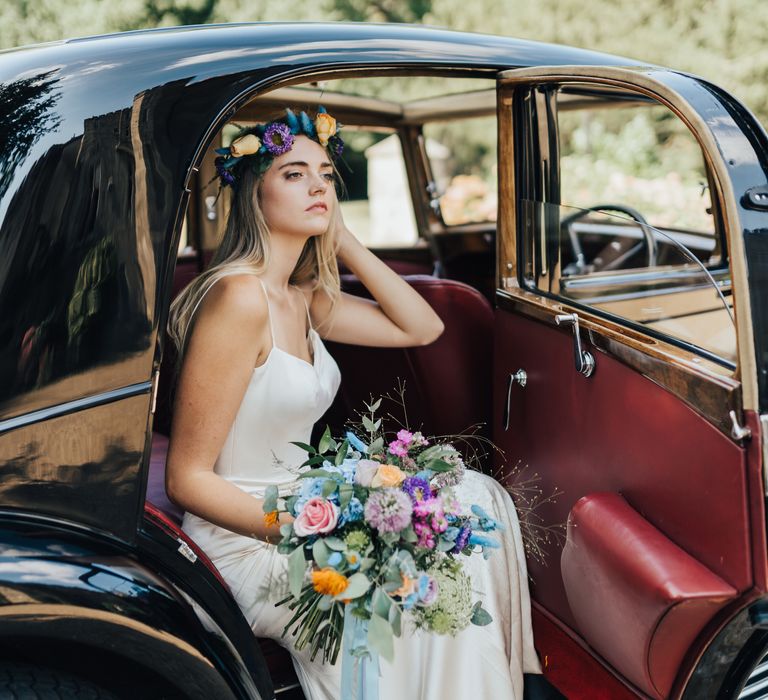 Bride exits car in vibrant flower crown and bright wedding bouquet with blue, purple, pink and orange flowers