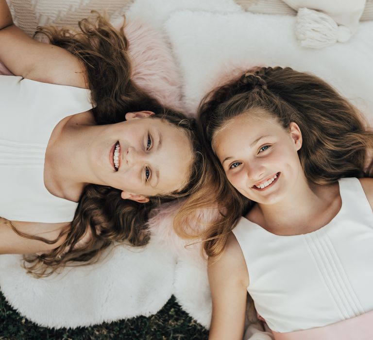 Young bridesmaids smile inside the lace teepee with pink fluffy pillows