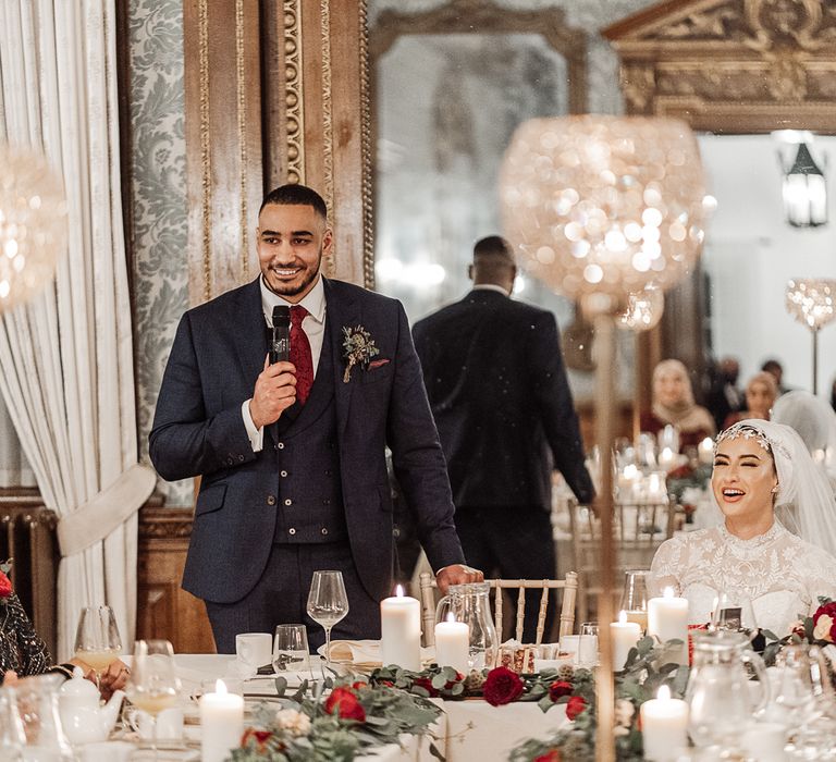 Groom speech at intimate micro wedding with red roses, foliage and pilar candles