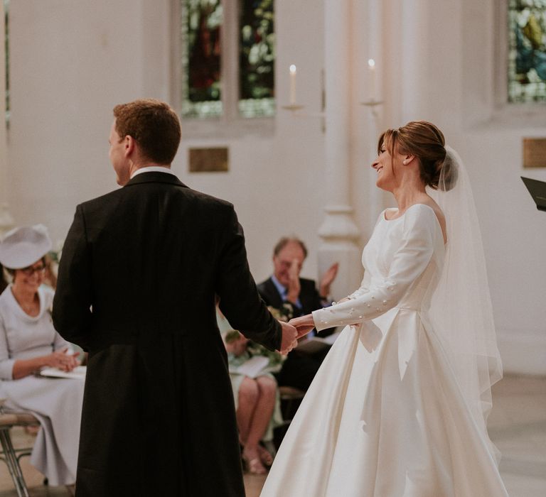 Bride and groom holding hands with pearl sleeved wedding dress